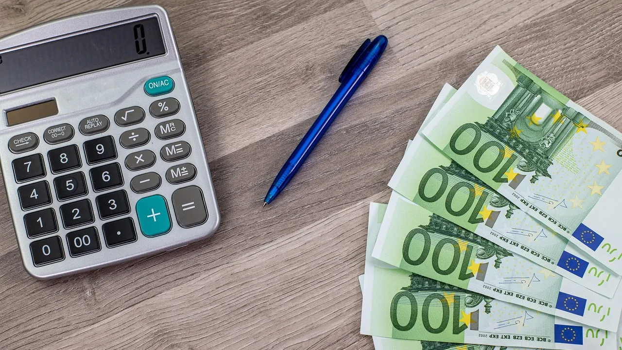 Rekenmachine, pen en een waaier van euro-biljetten op een houten bureau